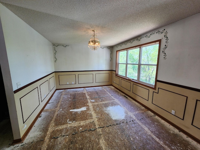 3458 Savannah Ave, White Bear Lake, MN 55110 - unfurnished dining area with a wainscoted wall, a decorative wall, a chandelier, and a textured ceiling
