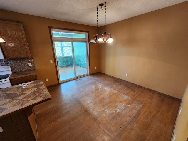 3458 Savannah Ave, White Bear Lake, MN 55110 - unfurnished dining area featuring light wood finished floors, a chandelier, baseboards, and a textured ceiling