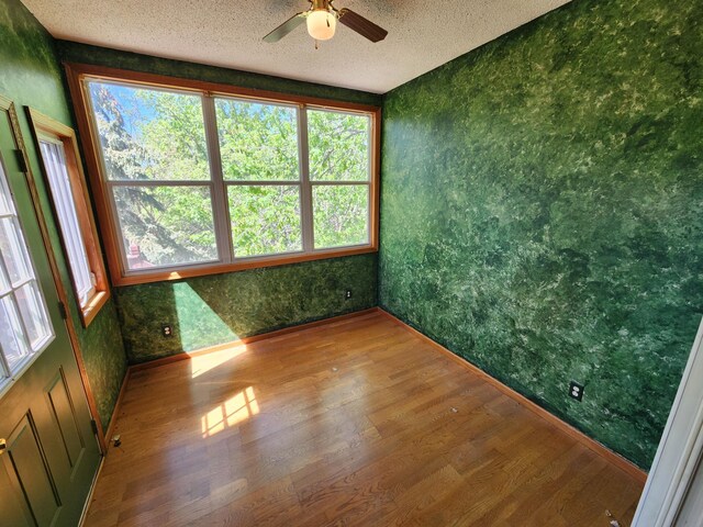 3458 Savannah Ave, White Bear Lake, MN 55110 - spare room featuring wood finished floors, wallpapered walls, ceiling fan, a textured ceiling, and healthy amount of natural light