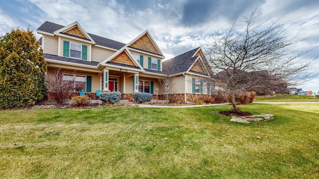 craftsman house featuring a porch, a front yard, stone siding, and roof with shingles