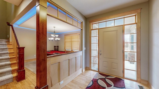 entrance foyer featuring light wood-style floors, stairway, a chandelier, and baseboards