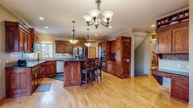 kitchen featuring appliances with stainless steel finishes, light wood finished floors, a kitchen bar, a center island, and a sink