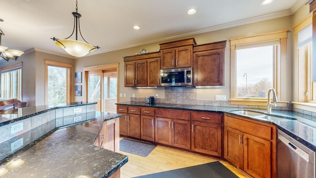 kitchen with stainless steel appliances, a sink, tasteful backsplash, light wood-style flooring, and pendant lighting