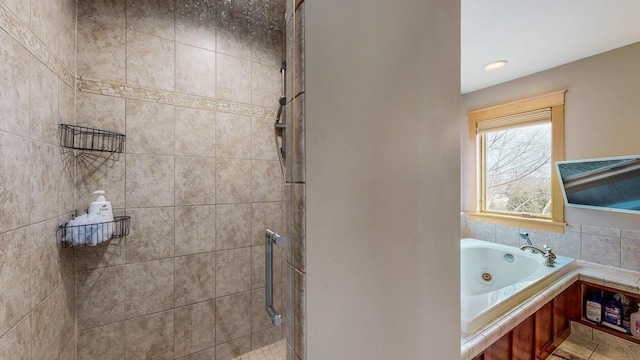 bathroom featuring a tile shower and a tub with jets