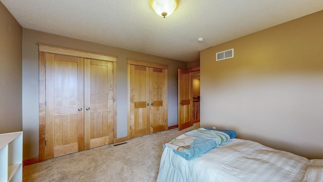bedroom with carpet floors, two closets, and baseboards