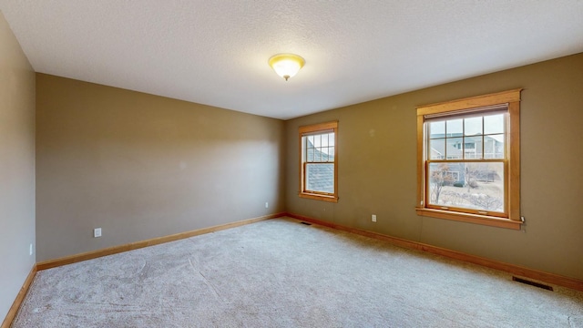 unfurnished room featuring carpet, baseboards, and a textured ceiling