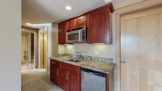 kitchen with stainless steel microwave, dishwashing machine, a sink, light stone counters, and recessed lighting