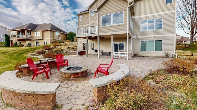 rear view of house featuring a fire pit, a balcony, a patio area, and a lawn