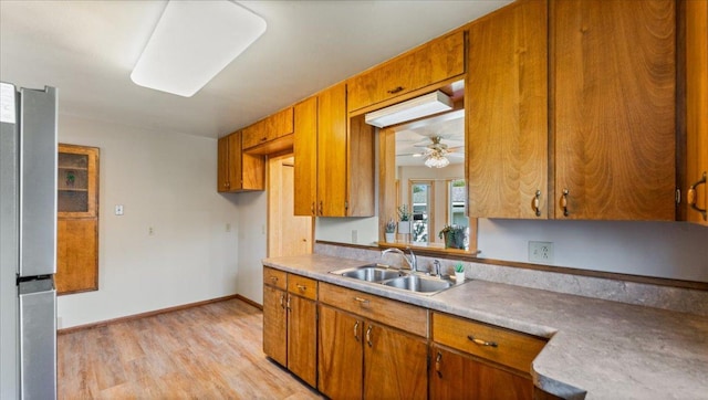 kitchen featuring a sink, light wood-type flooring, light countertops, and brown cabinetry
