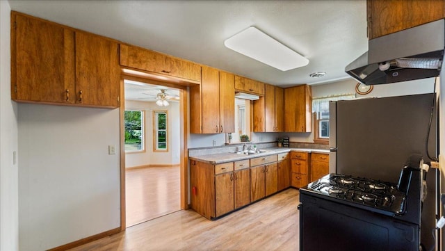 kitchen with a sink, light countertops, brown cabinetry, and light wood-style floors