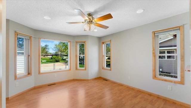 spare room with wood finished floors, a textured ceiling, baseboards, and ceiling fan