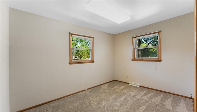 empty room featuring light colored carpet and baseboards