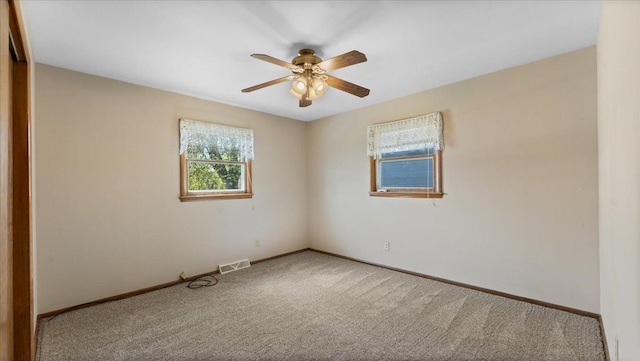 carpeted empty room with ceiling fan and baseboards