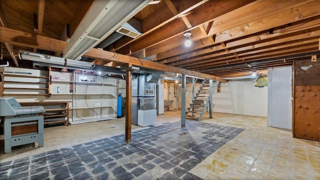 unfinished basement featuring heating unit and stairway