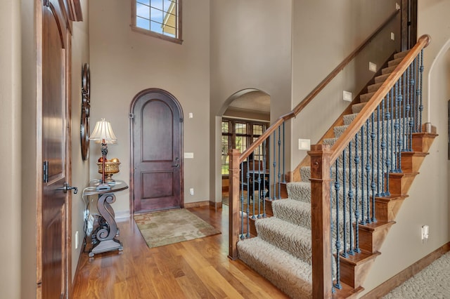 2255 Chelmsford Ln, Saint Cloud, MN 56301 - foyer featuring a high ceiling, arched walkways, wood finished floors, stairway, and baseboards