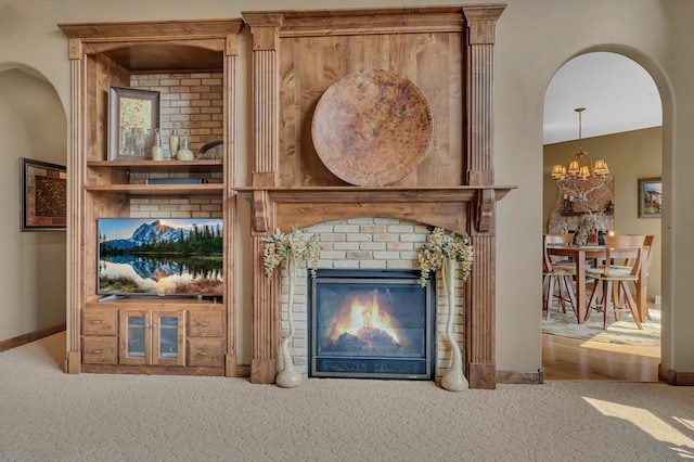 2255 Chelmsford Ln, Saint Cloud, MN 56301 - living area featuring carpet floors, a chandelier, a glass covered fireplace, baseboards, and arched walkways