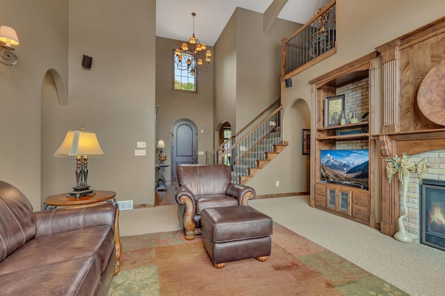 2255 Chelmsford Ln, Saint Cloud, MN 56301 - living room featuring a towering ceiling, carpet flooring, stairway, a chandelier, and a glass covered fireplace