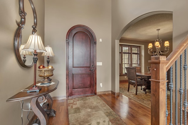 2255 Chelmsford Ln, Saint Cloud, MN 56301 - entryway with arched walkways, wood finished floors, a chandelier, baseboards, and a textured ceiling