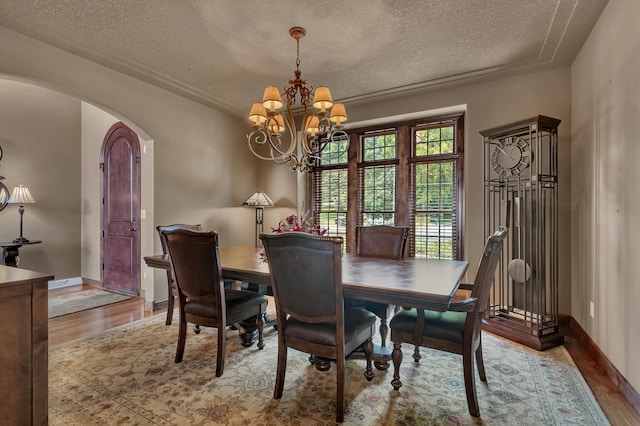 2255 Chelmsford Ln, Saint Cloud, MN 56301 - dining room featuring arched walkways, a textured ceiling, wood finished floors, a chandelier, and baseboards