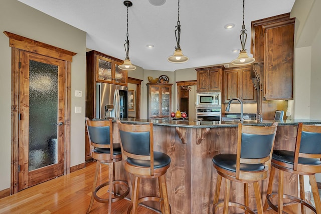 2255 Chelmsford Ln, Saint Cloud, MN 56301 - kitchen featuring appliances with stainless steel finishes, light wood-style floors, a peninsula, pendant lighting, and a sink