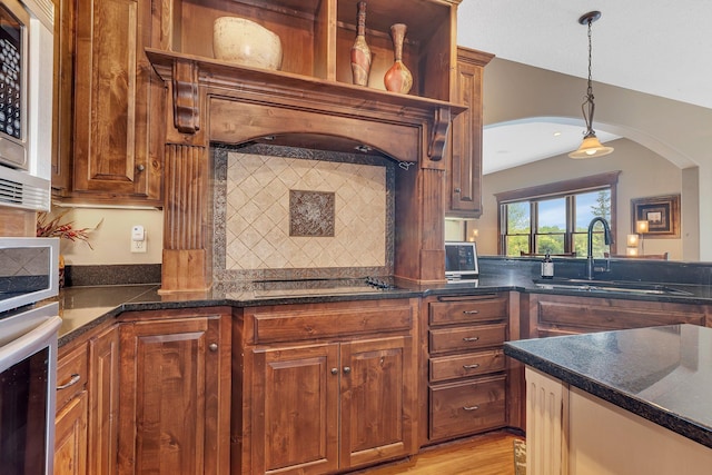 2255 Chelmsford Ln, Saint Cloud, MN 56301 - kitchen featuring a sink, arched walkways, dark countertops, stainless steel appliances, and pendant lighting