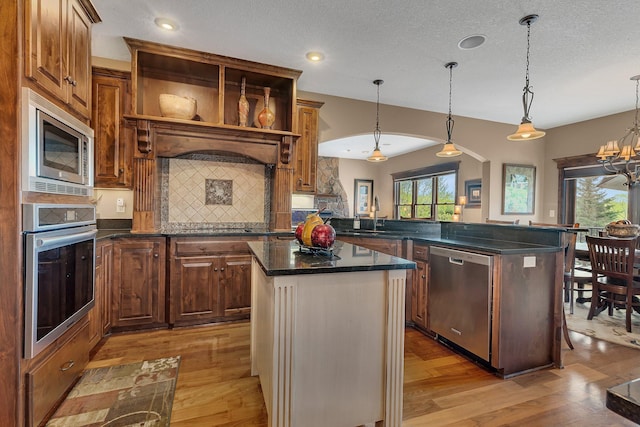 2255 Chelmsford Ln, Saint Cloud, MN 56301 - kitchen featuring stainless steel appliances, light wood finished floors, backsplash, a kitchen island, and a peninsula