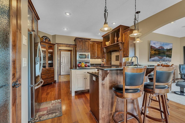 2255 Chelmsford Ln, Saint Cloud, MN 56301 - kitchen with stainless steel appliances, a peninsula, a breakfast bar area, wood finished floors, and recessed lighting