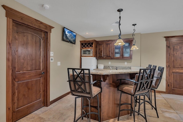 2255 Chelmsford Ln, Saint Cloud, MN 56301 - kitchen with fridge, a kitchen breakfast bar, baseboards, light stone countertops, and glass insert cabinets