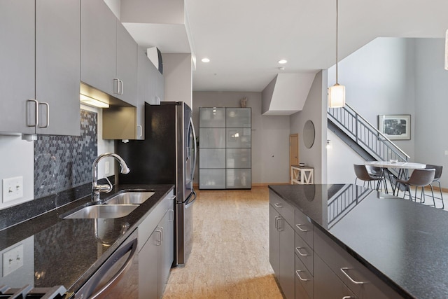 kitchen featuring a sink, dishwasher, tasteful backsplash, pendant lighting, and dark stone counters