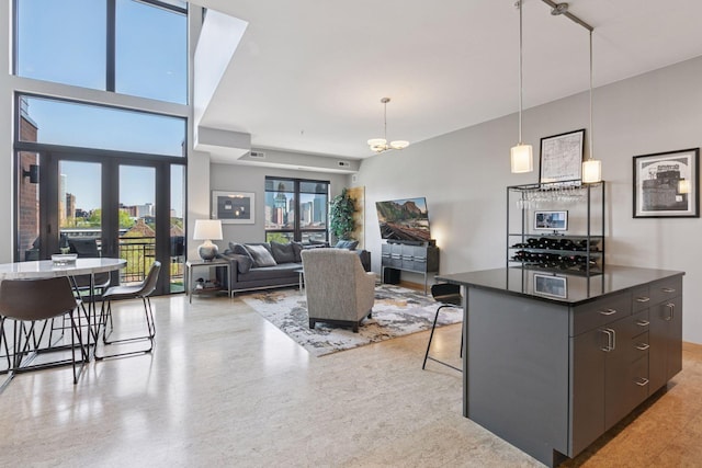 kitchen featuring dark countertops, pendant lighting, a chandelier, a kitchen breakfast bar, and a kitchen island