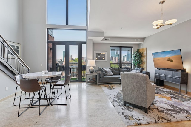 living area featuring stairway, a chandelier, speckled floor, and french doors