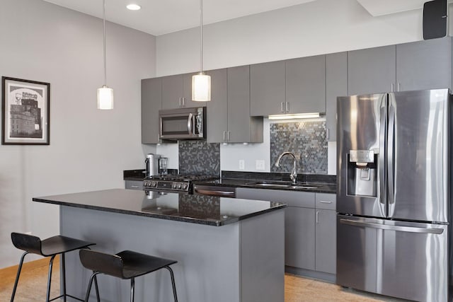 kitchen with appliances with stainless steel finishes, a sink, gray cabinets, a breakfast bar area, and recessed lighting