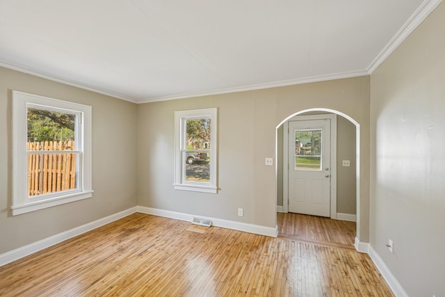 2647 Abbott Ave N, Robbinsdale, MN 55422 - empty room with healthy amount of natural light, arched walkways, light wood-style flooring, ornamental molding, and baseboards