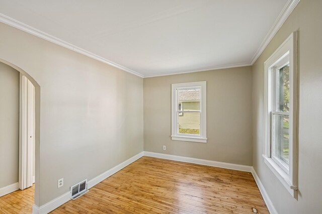 2647 Abbott Ave N, Robbinsdale, MN 55422 - empty room with light wood finished floors, plenty of natural light, arched walkways, crown molding, and baseboards