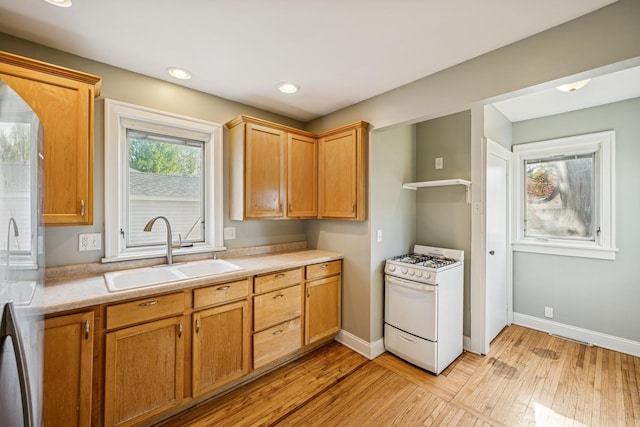 2647 Abbott Ave N, Robbinsdale, MN 55422 - kitchen with white range with gas stovetop, a sink, light wood-type flooring, light countertops, and baseboards