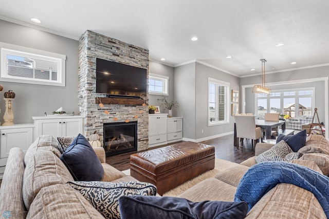 living area with wood finished floors, a stone fireplace, recessed lighting, baseboards, and crown molding