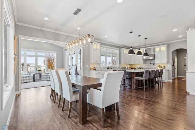 dining room featuring arched walkways, ornamental molding, dark wood finished floors, recessed lighting, and baseboards