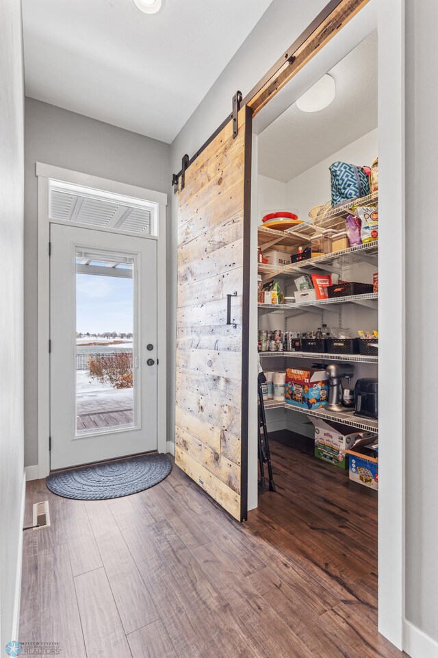 doorway to outside with wood finished floors and a barn door
