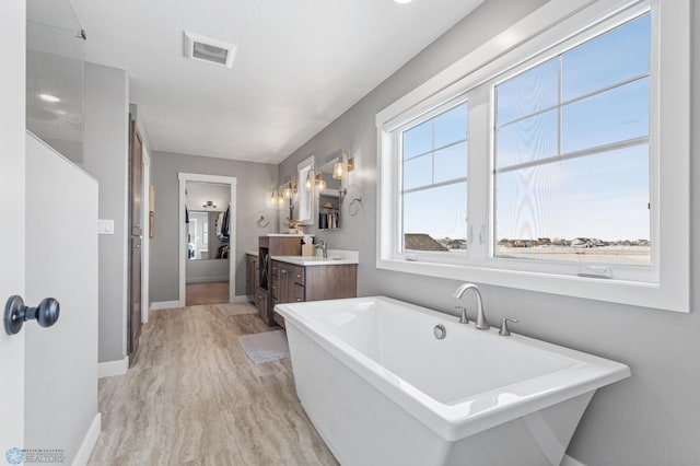 full bathroom with vanity, a freestanding tub, and baseboards