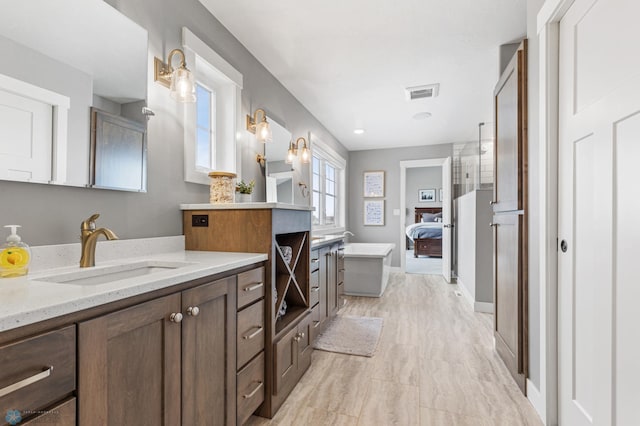 bathroom featuring a freestanding tub, two vanities, and an enclosed shower