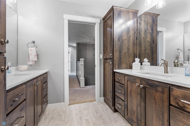 full bath with two vanities, baseboards, and marble finish flooring