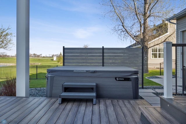 deck featuring a hot tub and fence