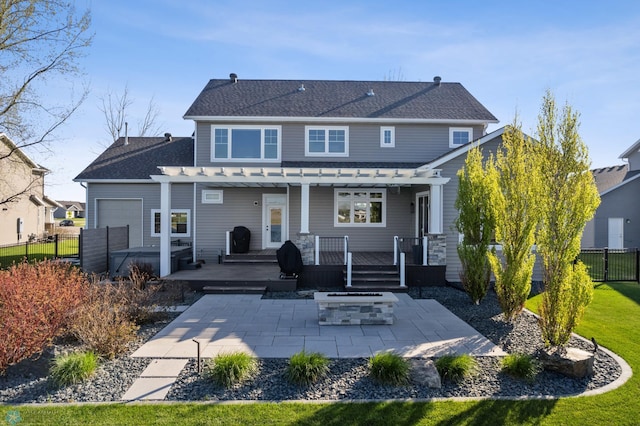 rear view of house with a fire pit, a pergola, a patio area, fence, and a deck