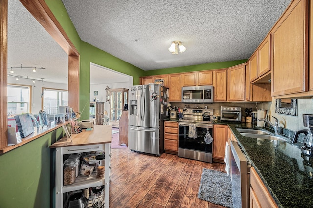 2231 Penn Pl Unit 114, North Saint Paul, MN 55109 - kitchen featuring appliances with stainless steel finishes, a textured ceiling, wood finished floors, a sink, and dark stone countertops