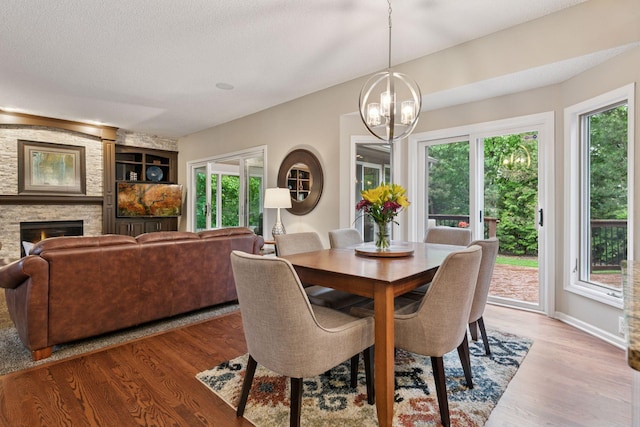 13148 Crolly Ct, Rosemount, MN 55068 - dining area with a chandelier, light wood-type flooring, a fireplace, a textured ceiling, and built in shelves