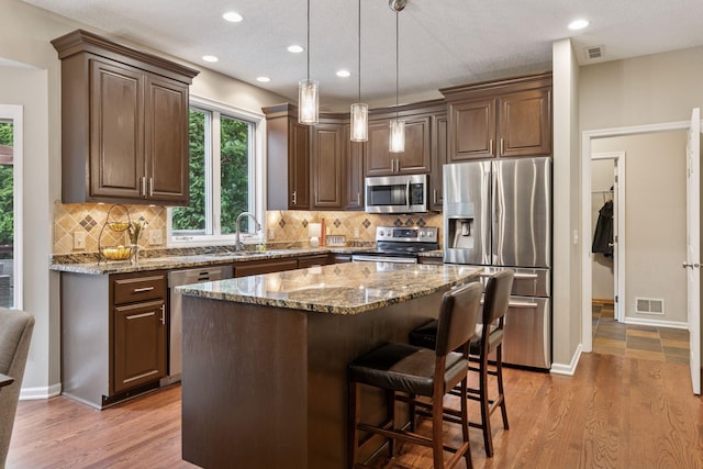 13148 Crolly Ct, Rosemount, MN 55068 - kitchen featuring appliances with stainless steel finishes, a sink, stone countertops, recessed lighting, and light wood-style flooring
