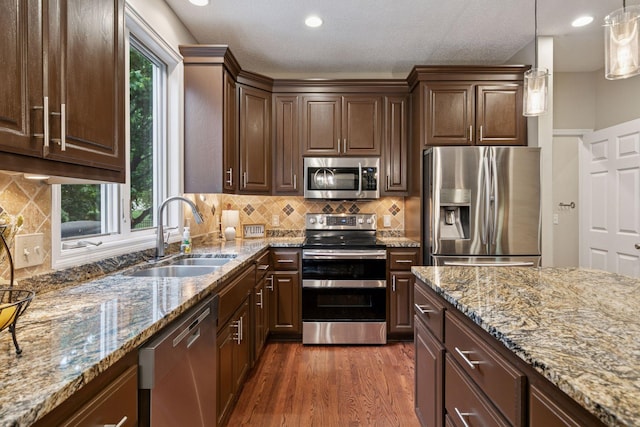 13148 Crolly Ct, Rosemount, MN 55068 - kitchen with stainless steel appliances, a sink, dark wood-style flooring, light stone counters, and dark brown cabinetry