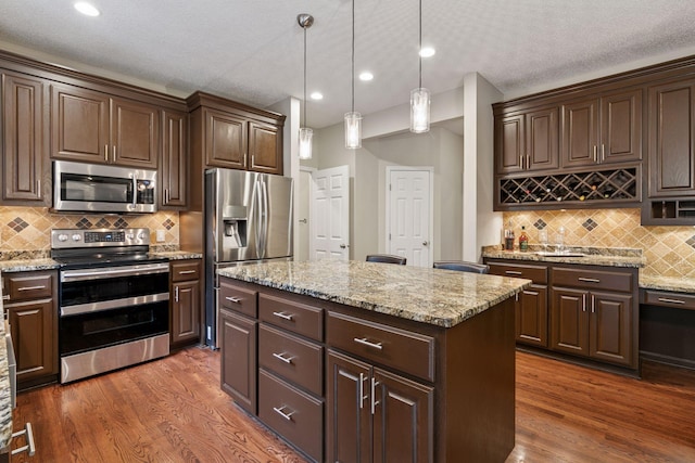13148 Crolly Ct, Rosemount, MN 55068 - kitchen with stainless steel appliances, a kitchen island, dark brown cabinets, dark wood-style floors, and recessed lighting
