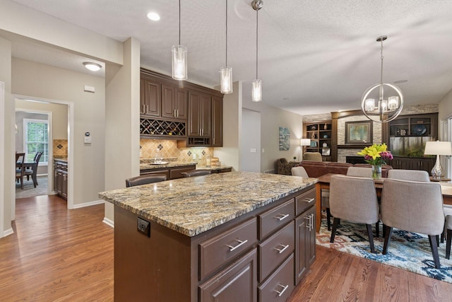 13148 Crolly Ct, Rosemount, MN 55068 - kitchen featuring wood finished floors, backsplash, light stone countertops, dark brown cabinets, and a textured ceiling