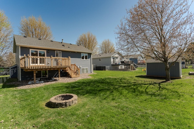 rear view of property featuring stairs, a deck, a fire pit, a storage unit, and an outdoor structure
